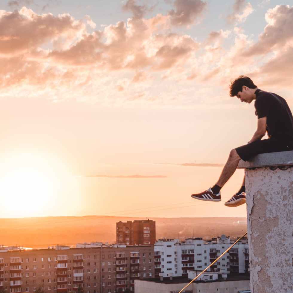 photo of a man sitting on the ledge of a building
